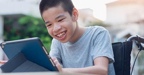 一名使用轮椅的在线学校学生在平板电脑上学习. 